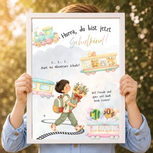 Puede incluir: Un póster enmarcado con una ilustración en acuarela de un niño con mochila y un cono escolar, rodeado de trenes, animales y globos. El texto dice: Hurra, du bist jetzt Schulkind!, 3... 2... 1... Start ins Abenteuer Schule!, y Viel Freude und ganz viel Spaß beim Lernen!