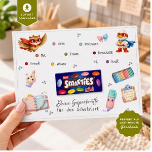 Puede incluir: Una tarjeta rectangular con una caja de Smarties mini en el centro, rodeada de ilustraciones de un búho, un pájaro superhéroe, una pluma estilográfica, un cuaderno, lápices de colores y un resaltador. El texto incluye "Deine Superkräfte für den Schulstart" y varias palabras en alemán.
