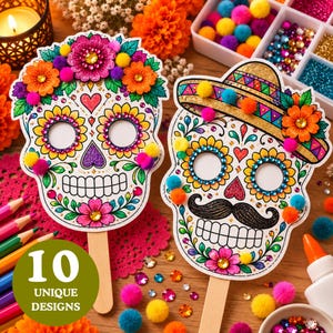 Puede incluir: Dos máscaras de calaveras de azúcar en palitos de madera, decoradas con purpurina colorida, pedrería y pequeños pompones. Una calavera tiene una corona floral, mientras que la otra lleva un sombrero y un bigote negro. Ambas tienen patrones florales.