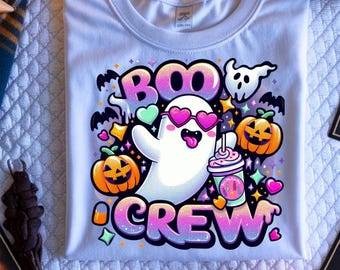 May include: White t-shirt with a Halloween-themed design. It features a cartoon ghost wearing heart-shaped sunglasses and the words "BOO CREW" in a colourful, gradient font. The design also includes pumpkins, bats, and stars.