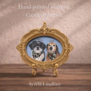 May include: An oval gold-toned ornate frame on a stand containing a painting of two dogs named Cooper and Emma, each wearing a patterned bandana. The text reads: Hand-painted with love. Captured forever. by HMA studioco.