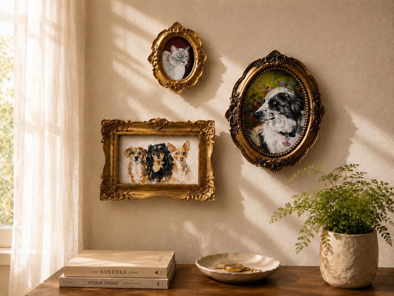 May include: Three ornate gold frames containing pet portraits are displayed on a wall. One oval frame holds a cat, another oval frame holds a black and white dog, and a rectangular frame holds three small dogs. The frames feature intricate carvings.