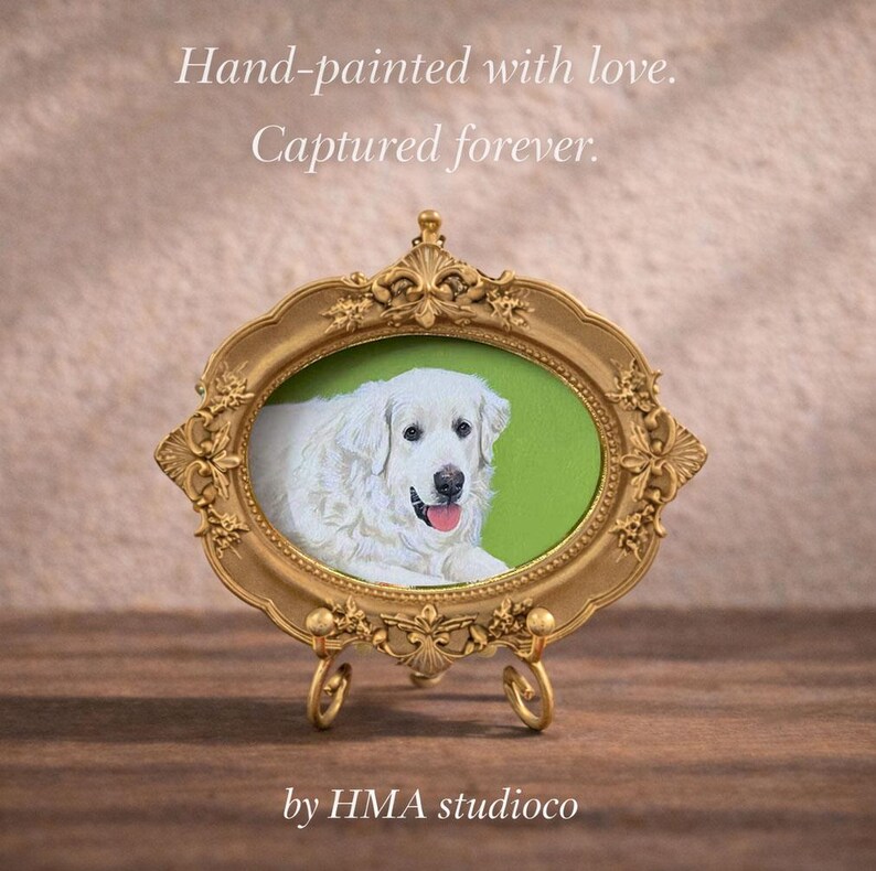 May include: An oval gold-toned ornate frame on a small stand containing a painting of a white dog with a pink tongue against a green background. The text reads: Hand-painted with love. Captured forever. by HMA studioco.