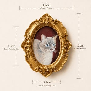 May include: An oval gold-colored frame with ornate floral detailing containing a painting of a light-colored cat with blue eyes against a dark red background. The frame measures 10 cm by 12 cm, with an inner painting area of 5.2 cm by 7.3 cm.