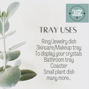 May include: A white background with a green plant on the left side of the image. The text "TRAY USES" is in black text at the top of the image. Below the text is a list of uses for a tray, including "Ring/Jewelry dish", "Skincare/Makeup tray", "To display your crystals", "Bathroom tray", "Coaster", "Small plant dish", and "many more..."