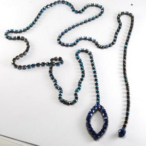 May include: A long blue rhinestone chain necklace with a teardrop-shaped pendant.