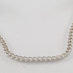 May include: A silver chain necklace with a curb link style.
