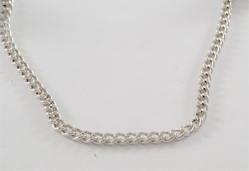May include: A silver chain necklace with a curb link style.