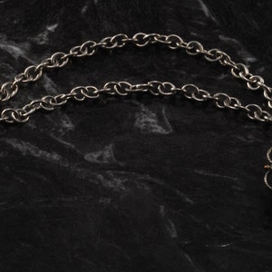 May include: A silver chain necklace with two turquoise flower-shaped pendants. Each pendant has a central turquoise stone surrounded by smaller turquoise stones.