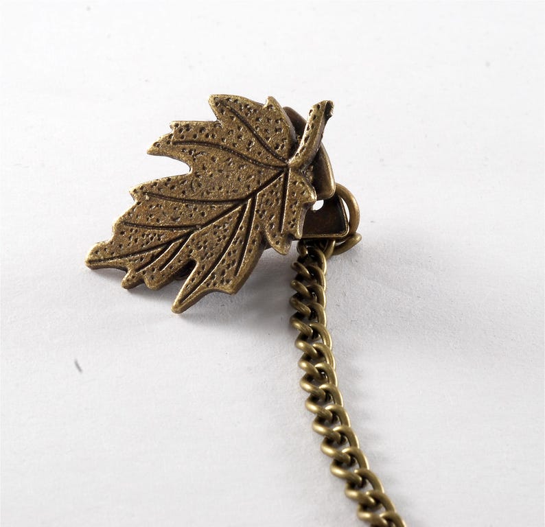 May include: A bronze leaf charm with a chain attached. The leaf is detailed with a textured surface.