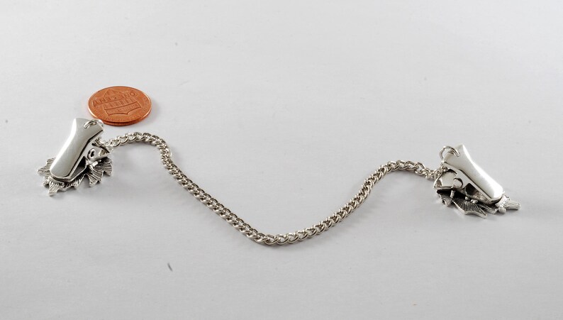 May include: Silver tone chain with two decorative clips on each end. The clips are shaped like leaves and have a silver tone finish.