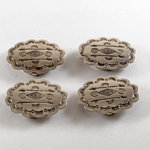 May include: Four silver-colored oval buttons with a scalloped edge. Each button features an engraved design of a diamond shape with arrows and lines. The buttons are likely for clothing or craft projects.