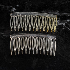 May include: Two clear plastic hair combs, one with a gold tint and the other with a clear finish. Both combs have a curved shape and fine teeth.