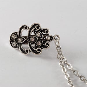 Puede incluir: Pinza para el pelo de plata con un dise&ntilde;o decorativo y brillantes transparentes. La pinza est&aacute; unida a una cadena de plata.