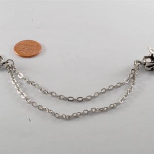 Puede incluir: Un par de broches de chal en forma de hoja de tono plateado conectados por una cadena doble.