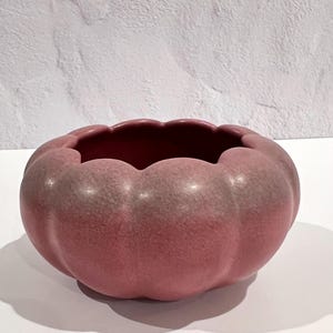 Może przedstawiać: Różowa ceramiczna miska z falistym brzegiem i fakturowaną powierzchnią. Miska ma kształt dyni.
