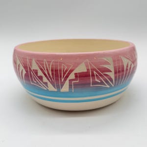 May include: A white ceramic mug with a black handle and the text "But First, Coffee" in a bold, black font. The mug is sitting on a wooden surface. The mug is approximately 4 inches tall.