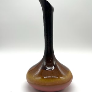 Könnte beinhalten: Eine hohe, schlanke Vase mit bauchigem Boden und einem gebogenen, länglichen Hals. Die Vase weist einen Farbverlauf auf, der von einem rosa Sockel zu einem gelbbraunen Mittelteil und einem dunkelbraunen bis schwarzen Hals übergeht. Die Vase ist wahrscheinlich aus Keramik.