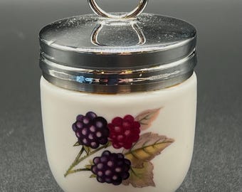 Könnte beinhalten: Ein weißer Eierbecher aus Keramik mit silbernem Deckel und Griff. Der Becher ist mit einer farbenfrohen Illustration von Brombeeren und Blättern verziert. Der Eierbecher hat einen Sockel.
