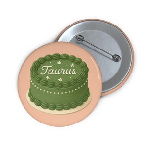 Puede incluir: Un pastel verde con glaseado blanco y la palabra "Taurus" escrita en él. El pastel está sobre un fondo rosa.