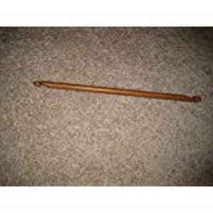 Puede incluir: Un gancho de ganchillo de madera con un acabado marrón.