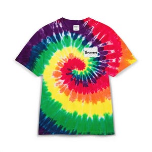 May include: A tie-dye t-shirt with a spiral pattern in vibrant rainbow colors. The shirt features a white rectangular patch with the Playboy logo. The shirt has a crew neck and short sleeves.