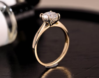 May include: A gold engagement ring with a large, round, clear center stone and smaller clear stones around the band.