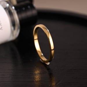 May include: A simple gold band ring with a smooth, polished finish.