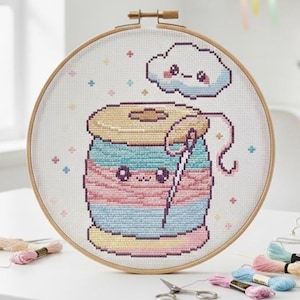 May include: A cross-stitch embroidery hoop featuring a cute spool of thread with a needle and a smiling cloud. The design uses pastel colors and is set against a white background. Embroidery floss and scissors are on the table.