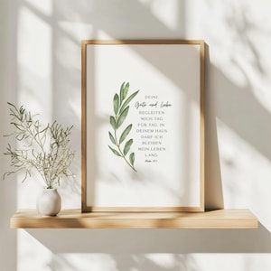 Könnte beinhalten: Gerahmter Druck mit dem deutschen Text "DEINE Gute und Liebe" und einer grünen Blattillustration. Der hellbraune Rahmen befindet sich auf einem Holzregal, zusammen mit einer kleinen Vase und einer Pflanze. Der Druck ist in einem rechteckigen Rahmen.