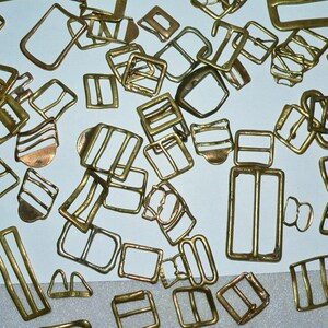May include: A collection of antique brass buckles, some with a striped design, in various shapes and sizes.