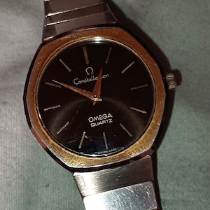 Vintage Omega quartz analogue mens watch, black dial, gold bezel, applied gold furnishings, serviced with new movement