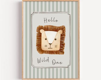 May include: A framed art print featuring a watercolor illustration of a lion's face. The lion is brown with a white face and a small nose. The text "Hello Wild One" is below the lion. The background has vertical stripes.