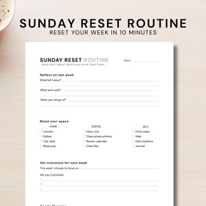 May include: A white printed planner titled "SUNDAY RESET ROUTINE" with prompts to reflect on the week and set intentions. The text includes "Reset your space, Reset your mind, Start Fresh." A cup of coffee sits in the upper left corner.