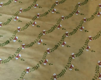 May include: A yellow fabric with a repeating pattern of green vines with white flowers and red accents. The fabric is a light weight and has a soft texture.