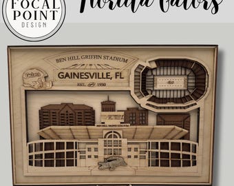 May include: A wooden laser-cut artwork featuring the words "Florida Gators" and a stadium design. The artwork includes the text "Ben Hill Griffin Stadium, Gainesville, FL, Est. 1930" and a logo for Focal Point Design. The design includes a football helmet and a gator.