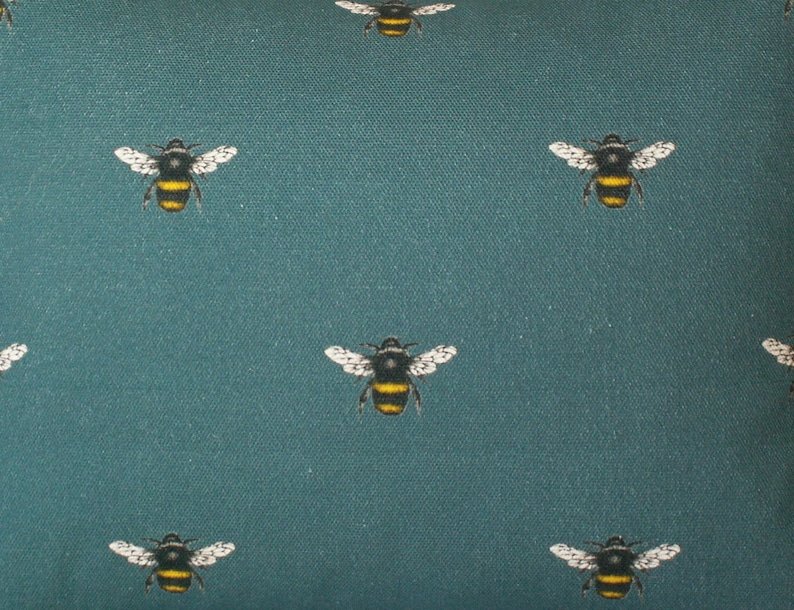 May include: Teal fabric with a repeating pattern of black and yellow bumblebees.