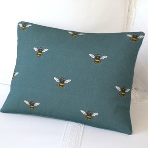 May include: Teal blue throw pillow with a repeating pattern of yellow and black bumblebees.