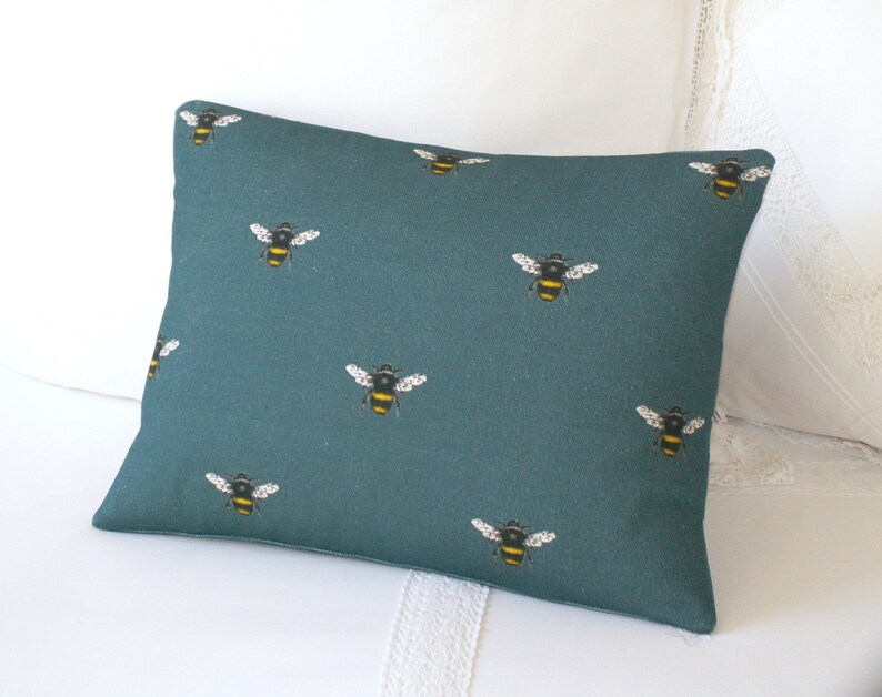 May include: Teal blue throw pillow with a repeating pattern of yellow and black bumblebees.