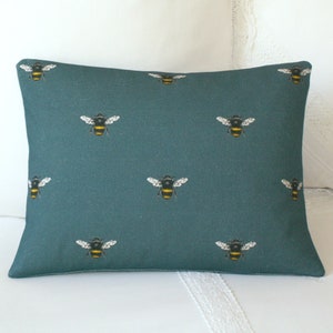 May include: Teal blue throw pillow with a repeating pattern of black and yellow bees.