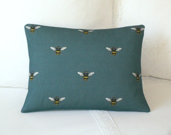 May include: Teal blue throw pillow with a repeating pattern of black and yellow bees.