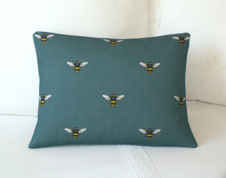 May include: Teal blue throw pillow with a repeating pattern of black and yellow bees.