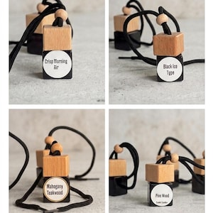 May include: Four car air fresheners with wooden tops and black cords. Each has a black base with a white label. The labels read "Crisp Morning Air", "Black Ice Type", "Mahogany Teakwood", and "Pine Wood".