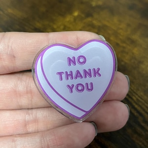 May include: A purple heart-shaped candy with the text "NO THANK YOU" in white letters.