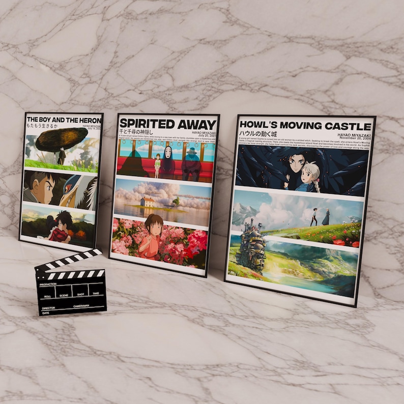 Pode incluir: Tr&ecirc;s cartazes de filmes emoldurados com ilustra&ccedil;&otilde;es de filmes do Studio Ghibli. Os cartazes s&atilde;o intitulados "O Menino e a Gar&ccedil;a", "A Viagem de Chihiro" e "O Castelo Animado".