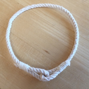 May include: A white rope bracelet with a simple knot closure.