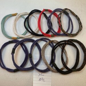 group of remainder string bracelets size extra large with notation XL 8 1/2" These bracelets are made with multiple strands of colored cotton cord bound with waxed thread whippings creating a fixed size slip on rope bracelet