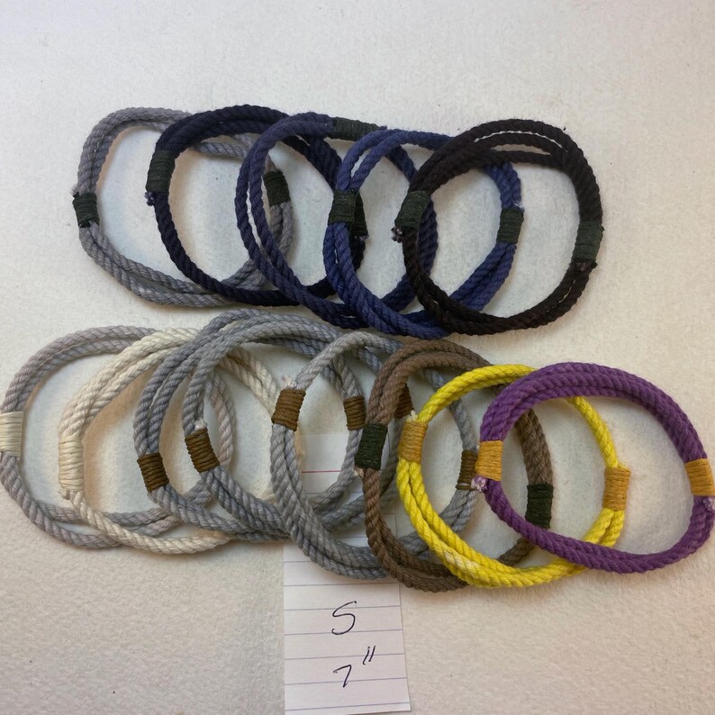 group of remainder string bracelets size small with a notation reading S 7" These bracelets are made with multiple strands of colored cotton cord bound with waxed thread whippings creating a fixed size slip on rope bracelet