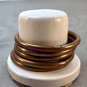 May include: A set of three circular, metallic, bronze-toned rings with a smooth, polished finish. Each ring features a small, visible hinge mechanism and a tiny screw, allowing the circular band to open and close securely for functional use.