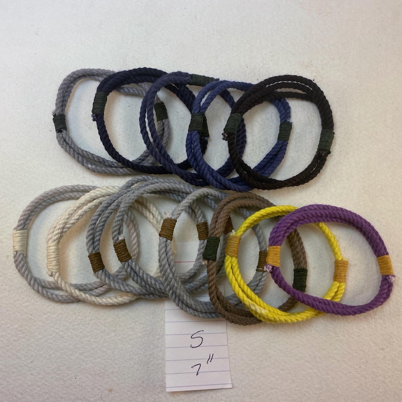 group of remainder string bracelets size small. These bracelets are made with multiple strands of colored cotton cord bound with waxed thread whippings creating a fixed size slip on rope bracelet